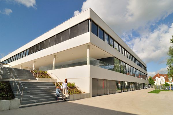 ein großes rechteckiges Gebäude, neben dem eine große Treppe auf einen gepflasterten Platz führt