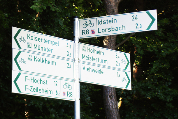 ein Schild mit diversen Fahrrad-Wegweisern in verschiedene Richtungen