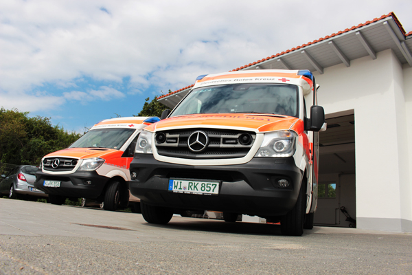zwei Rettungswagen, die vor einem weißen Gebäude mit offenem Garagentor parken