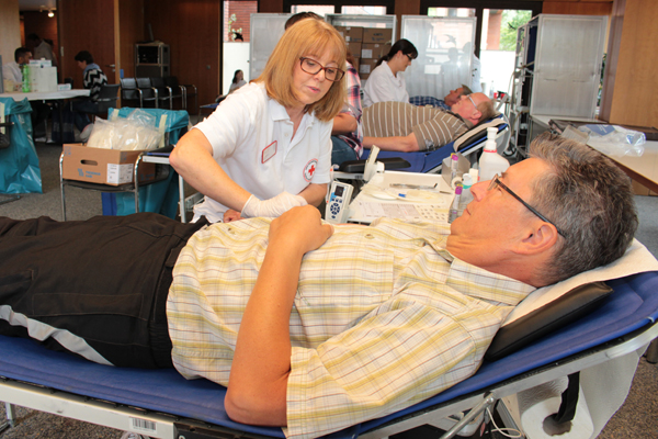 ein Raum mit mehreren Liegen, auf denen Männer liegen, denen von DRK-Mitarbeiterinnen Blut abgenommen wird