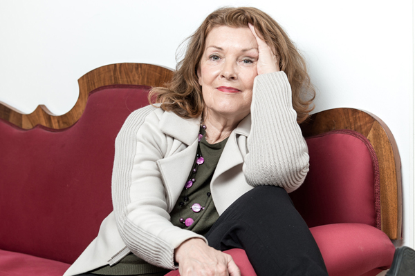 das Portrait einer Frau in heller Strickjacke auf einem roten Sofa