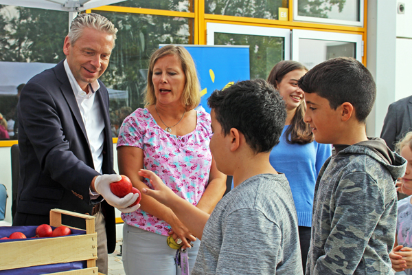 eine Frau und einen Mann, der Äpfel an einige Kinder verteilt, im Gespräch