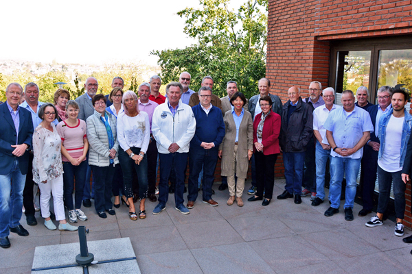 eine große Gruppe Personen, die sich auf einer Terrasse zum Gruppenbild aufgestellt hat