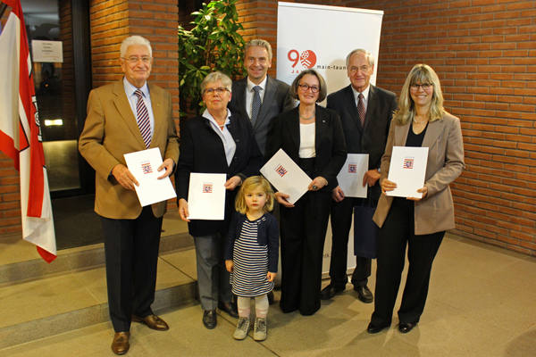 ein Gruppenfoto von drei Männern, drei Frauen und einem Kind, viele von ihnen mit Urkunden in der Hand