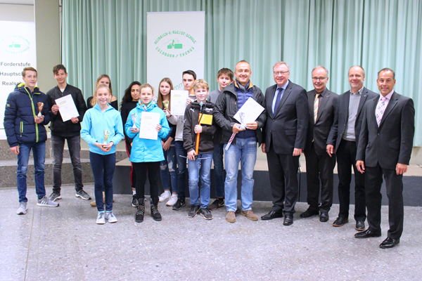 eine Gruppe Schüler mit Urkunden in den Händen, daneben einige Männer in Anzügen