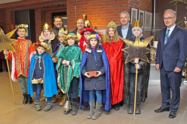 eine Gruppe als Sternsinger verkleideter Kinder und einige Männer aufgestellt zu einem Gruppenbild