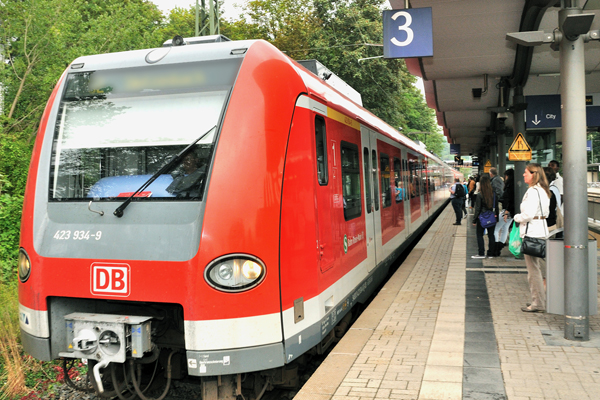 eine S-Bahn an einem Bahnsteig, auf dem Menschen stehen
