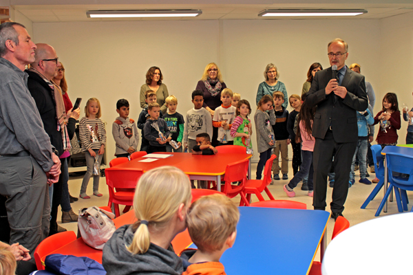 ein Mann mit Mikrofon inmitten vieler Kinder und Eltern