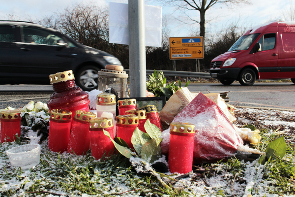 eine Straßenkreuzung, an der im Vordergrund Grablichter stehen