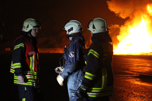 drei Feuerwehrleute vor einem Feuer
