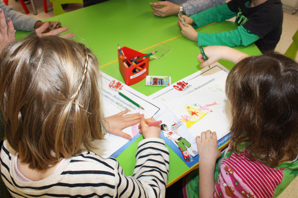 mehrere Kinder an einem Tisch, die mit Buntstiften malen