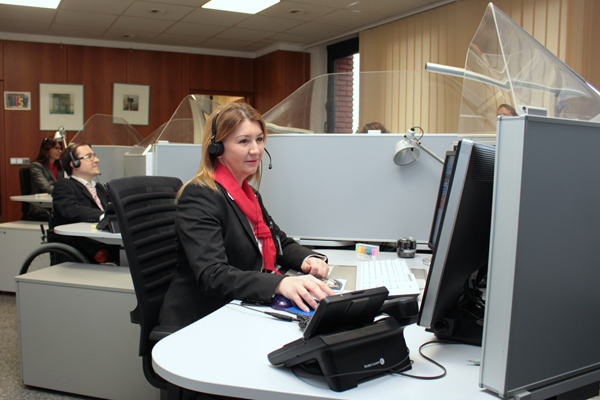 ein Call Center, in dem mehrere Personen mit Headsets an Schreibtsichen sitzen