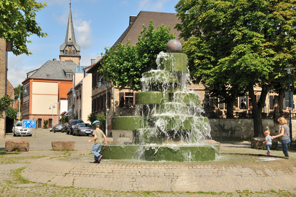 ein Brunnen in einer Alstadt, an dem zwei Kinder spielen