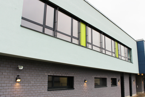 die Außenansicht eines Gebäudes mit einer großen Fensterfront im ersten Stock