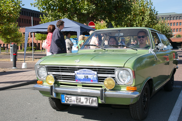 einen grünen Oldtimer von Opel in der Einfahrt zu einem großen Gebäude