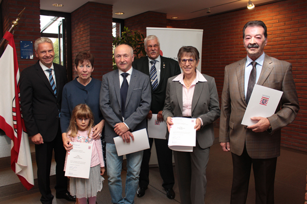 ein Gruppenbild mit zwei Frauen, vier Männern und einem Kind; einige von ihnen halten Urkunden in den Händen