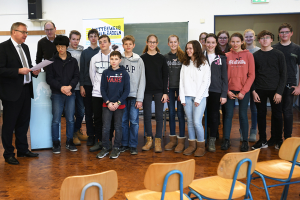 ein Mann liest einer Gruppe Schüler eine Urkunde vor