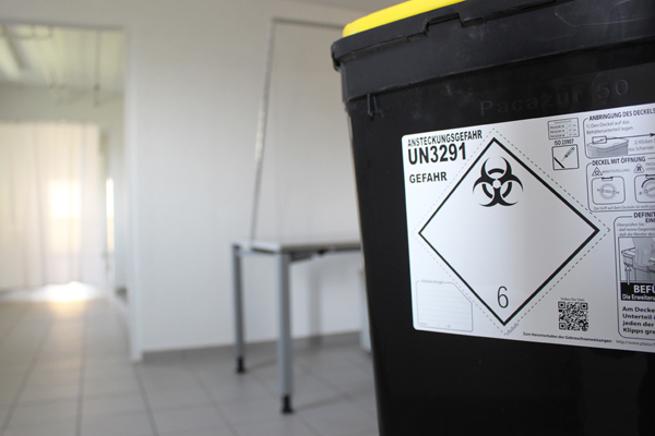 den Blick in einen Untersuchungsraum mit einem Behälter für ansteckendes Material