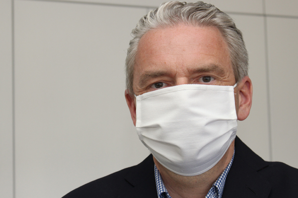 Portraitbild eines Mannes mit weißer Gesichtsmaske über Mund und Nase