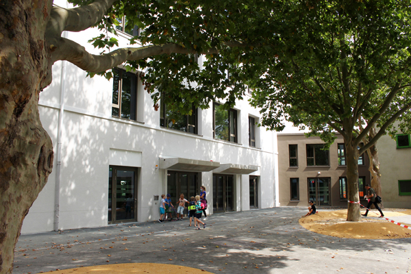 ein Innenhof mit Eingang zu einem Schulgebäude, vor dem einige Kinder stehen
