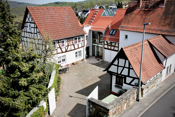 die Luftaufnahme mehrerer sanierter Fachwerkhäuser, die sich um einen gepflasterten Innenhof gruppieren