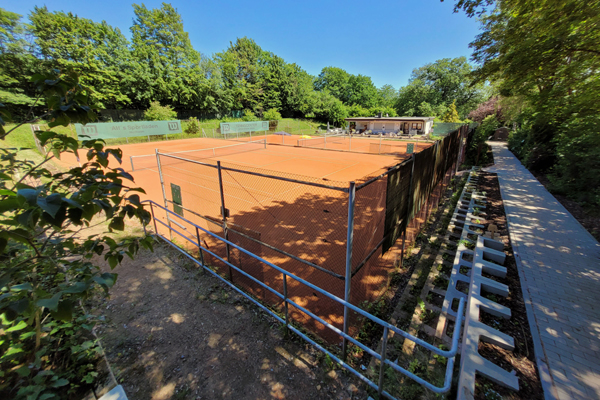 zwei Tennisplätze und im Hintergrund ein kleines Gebäude, umrahmt von Bäumen