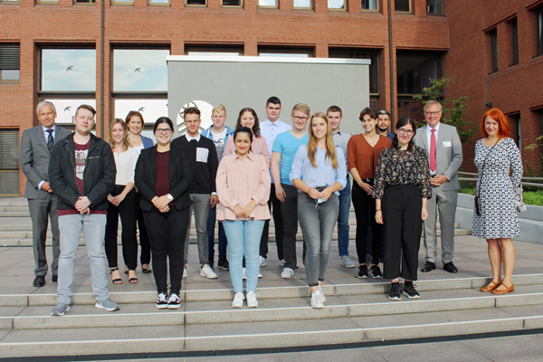 ein Gruppenbild mit 18 Personen auf einer Treppe vor einem Gebäude