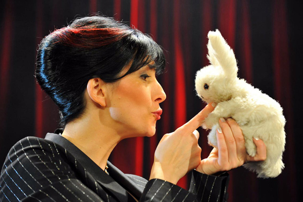 eine Frau, die ein Plüschkaninchen in der Hand hält und mit ihm spricht