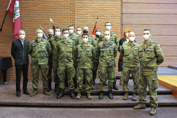 eine Gruppe Bundeswehrsoldaten, die sich mit einem Mann und einer Frau zu einem Gruppenfoto aufgestellt haben
