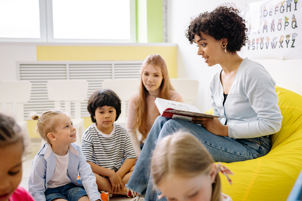 eine Kinderbetreuerin, die einer Gruppe Kinder ein Buch vorliest