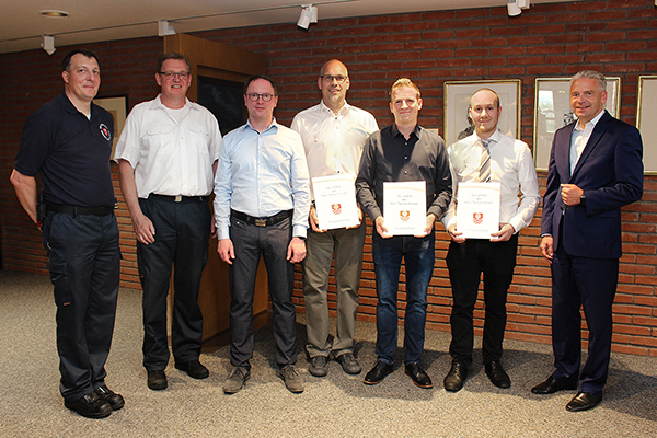 ein Gruppenfoto von sieben Männern, drei davon mit einer Urkunde in der Hand