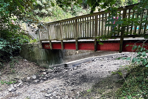 eine Holzbrücke über einem ausgetrocknetem Bach