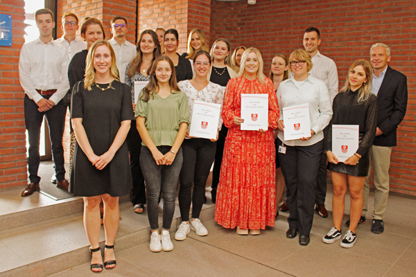 ein Gruppenbild, auf dem einige Personen Urkunden und Zeugnisse in den Händen halten