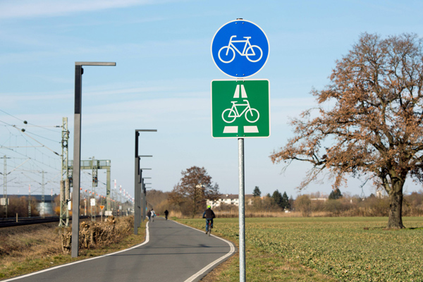 einen Radweg zwischen einem Feld und einer Bahnstrecke