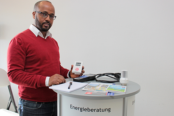 einen Mann mit einem Messgerät an einem Tisch mit Flyern, Geräten und der Aufschrift