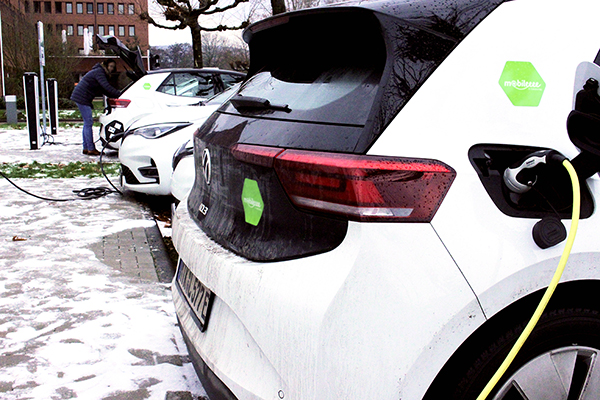 mehrere aufgereihte E-Autos an Ladestationen im Schnee
