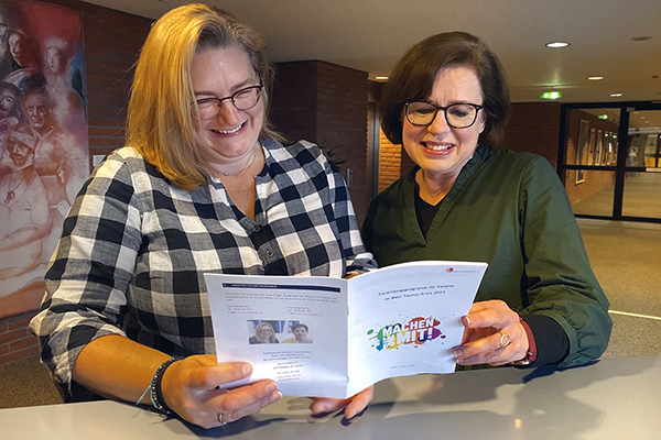 zwei Frauen betrachten einen Flyer mit dem Titel