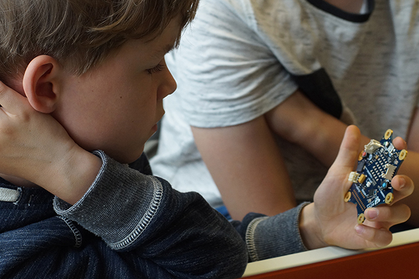 einen Schüler der Bauteilen eines Mini-Computers in der Hand hält