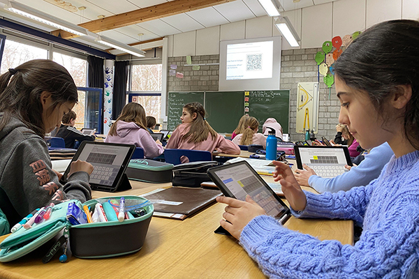 einen Klassenraum voller Schüler, die digital auf Tablets arbeitet