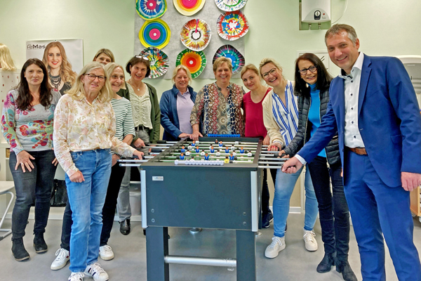 Kreisbeigeordneten Axel Fink mit Vertreterinnen des Kreises, der Caritas und dem Betreuungsteam der Taunusblickschule in einem bunt dekorierten Raum an einem Tischkicker