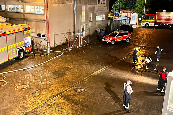 Feierwehrleute im Einsatz auf einer Straße mit Feuerwehrfahrzeugen
