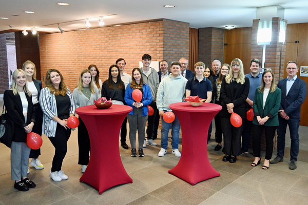 eine Gruppe an Menschen, ein Teil davon hält Luftballons in der Hand