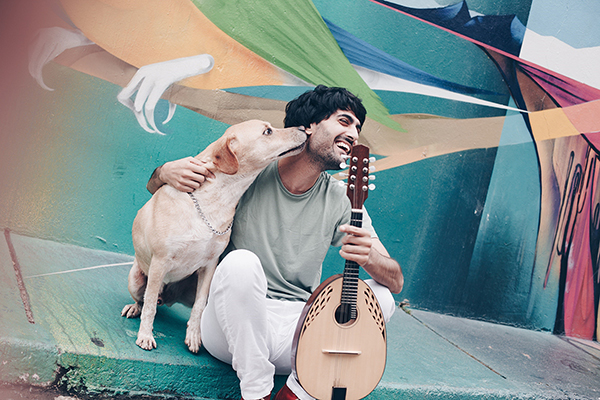 einen Mann mit seinem Hund und seinem Musikinstrument vor einer Grafittiwand