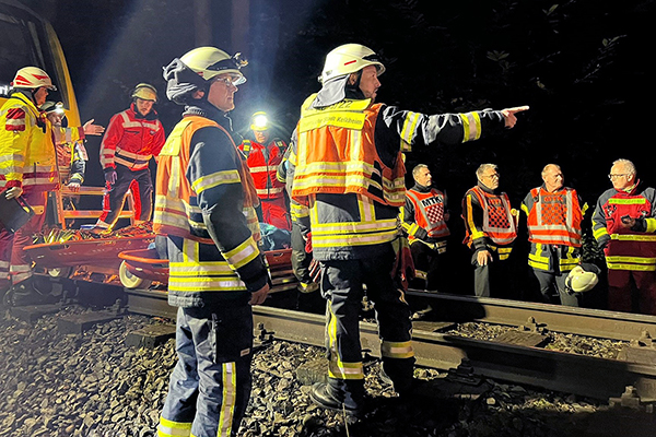 Feuerwehreinsatzkräfte auf Gleisen vor einem Zug während einer Übung