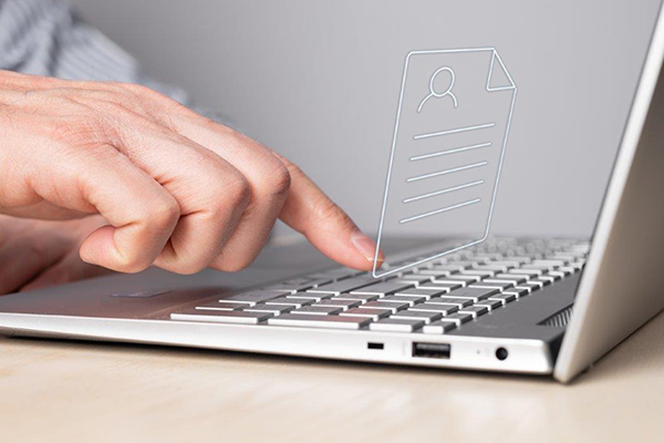 eine Hand tippt auf eine Laptop Tastatur, darüber erscheint ein Dokumentensymbol