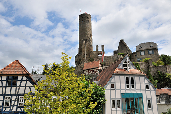 eine Burgruine über einer Altstadt mit Fachwerkhäusern.