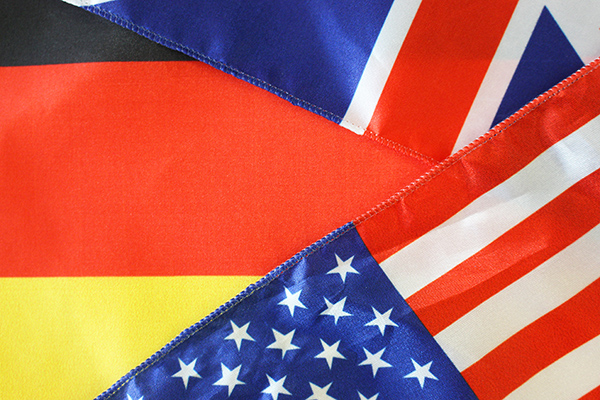 Ausschnitte einer deutschen, einer britischen und einer amerikanischen Fahne, die übereinander liegen.