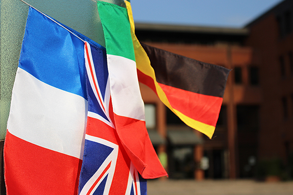 Fähnchen mit den deutschen, italienischen, britischen und französischen Landesfarben, die an einer Säule vor dem Landratsamt hängen.