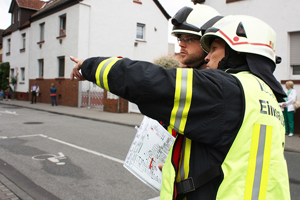 zwei Feuerwehrleute, die sich an einem Plan orientieren.