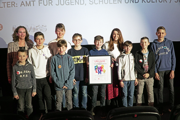 zehn Jugendliche und eine Frau, die sich auf einer Bühne zum Gruppenbild mit Urkunde aufgestellt haben